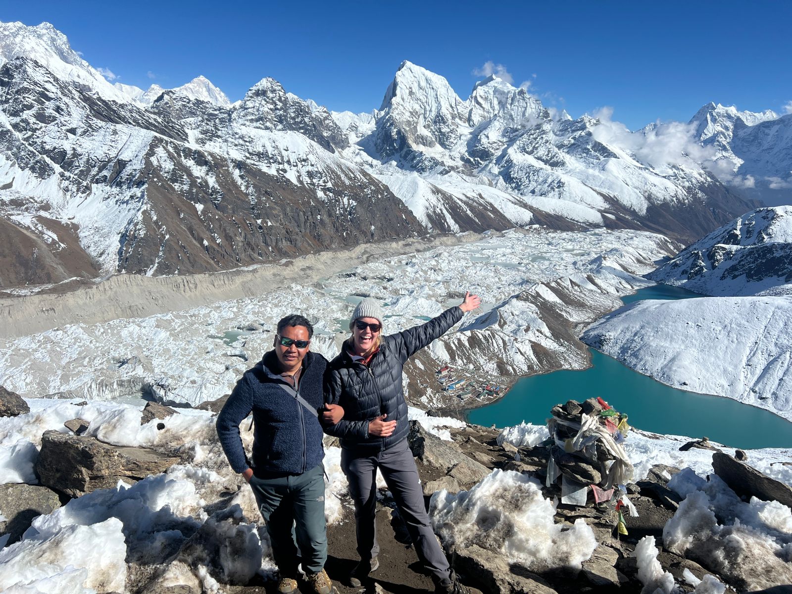 Two trekkers at Gokyo Ri summit with turquoise lakes and glacier behind